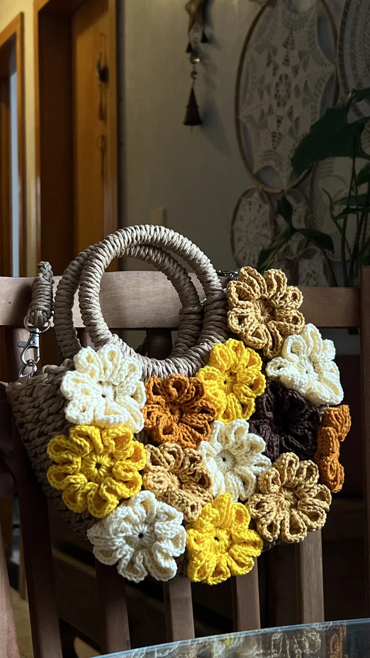 Bolsa de palha customizada com flores de crochê pendurada em cadeira de palha boho