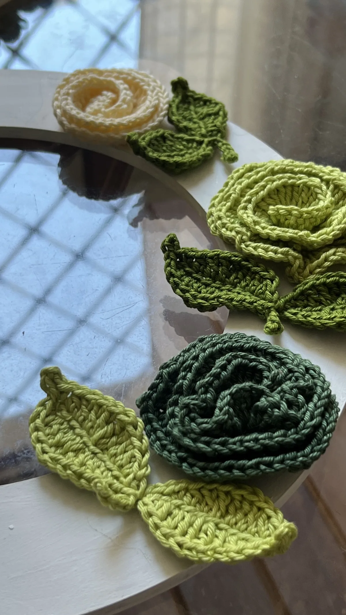 Detalhe da Flor Alice em crochê na cor creme com folhas verdes