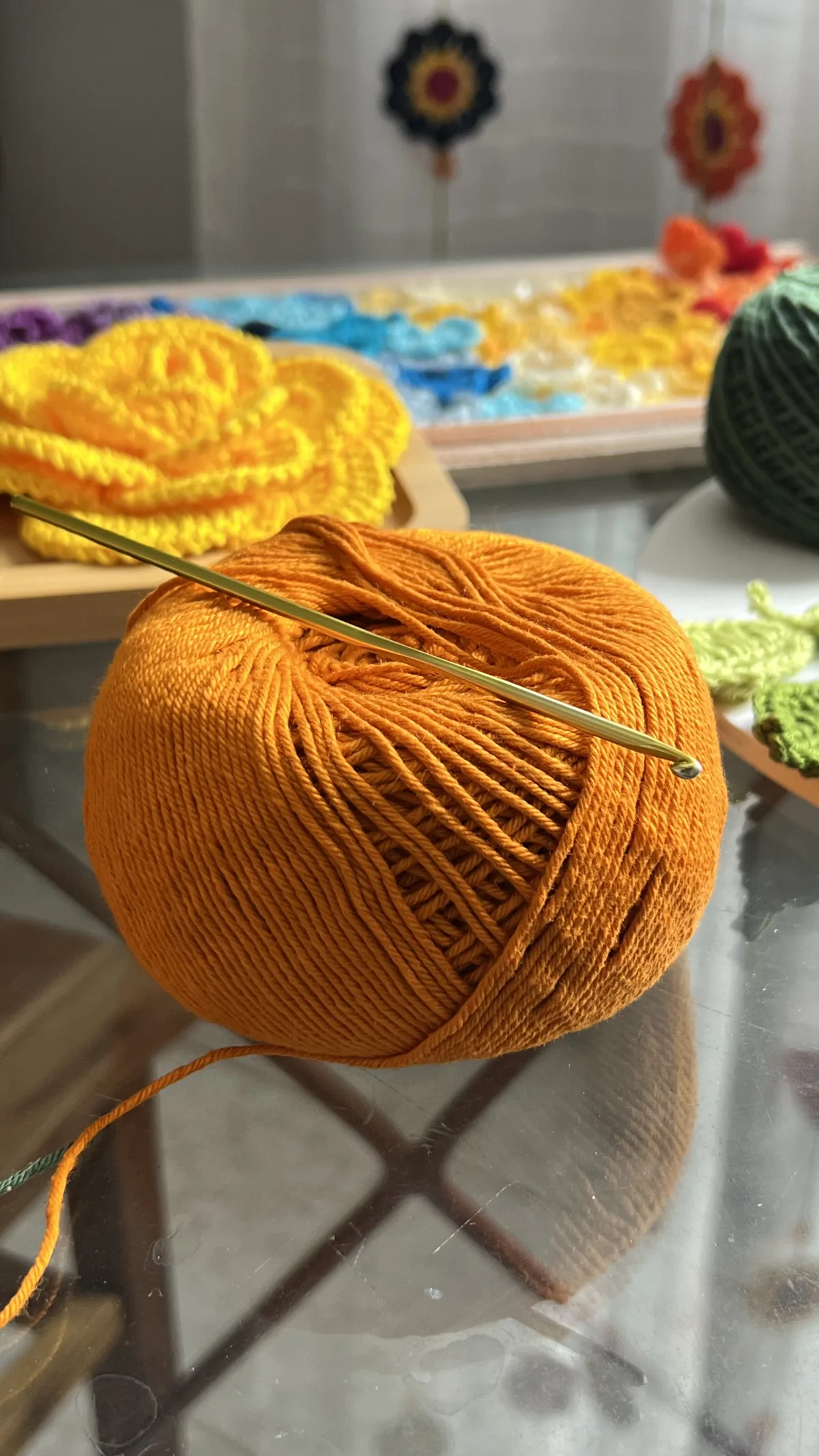 Novelo de linha laranja com Flores Regina em crochê amarelas ao fundo