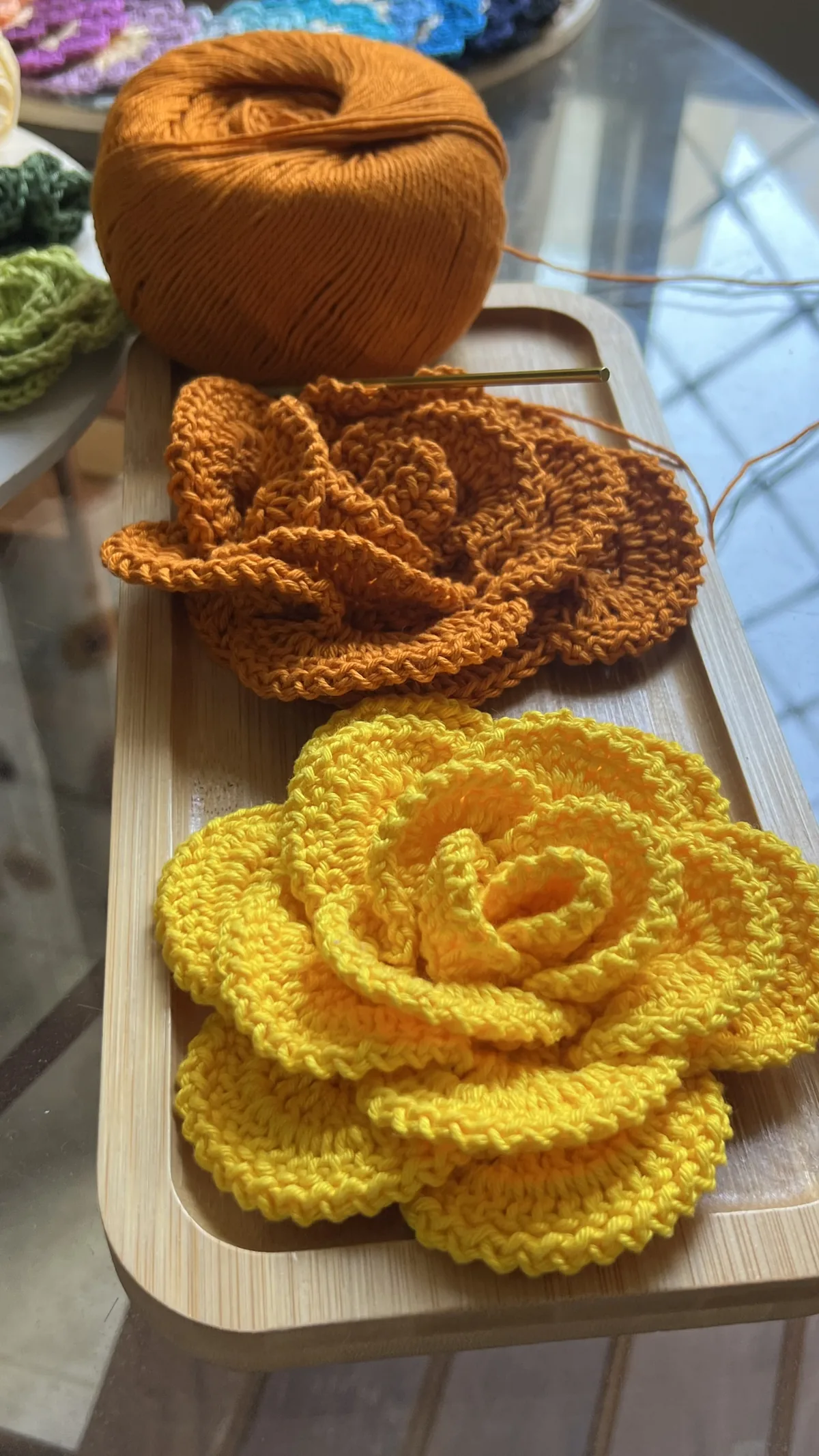 Flor Regina em crochê nas cores laranja e amarelo sobre a mesa de trabalho