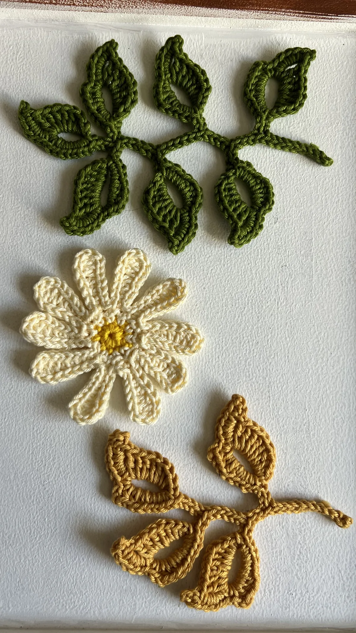 Ramo de folhas verde, flor margarida e ramo dourado em crochê