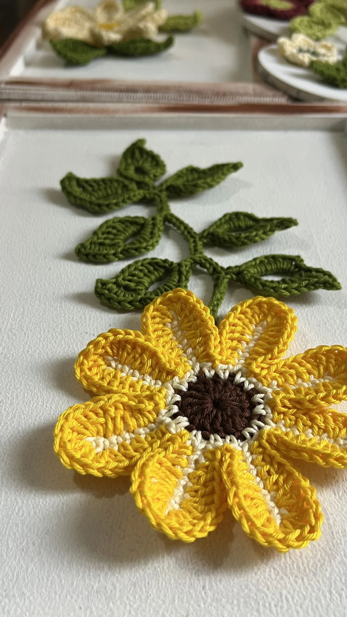 Girassol de crochê composto com ramo de folhas